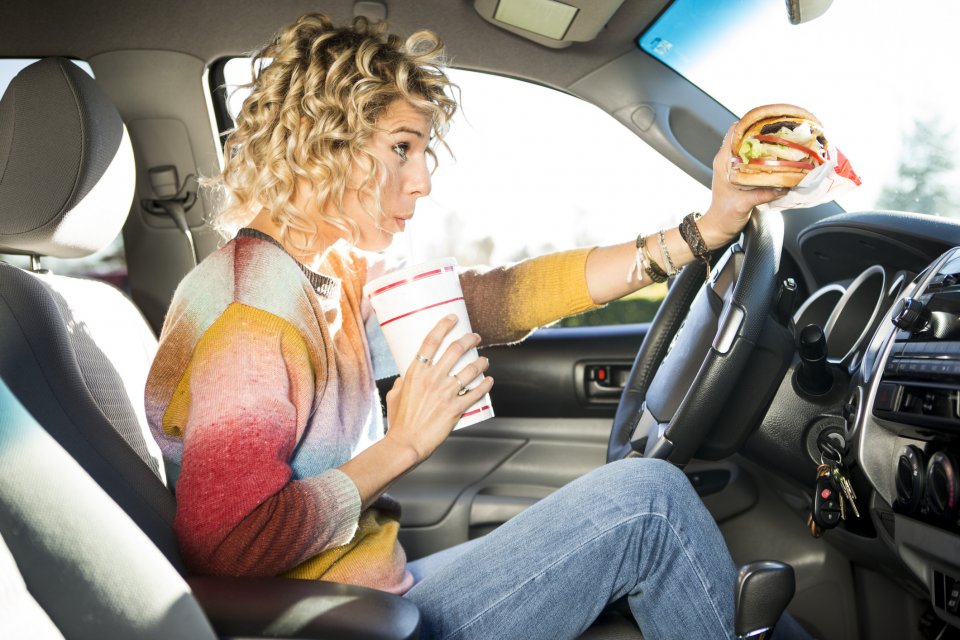 Verkeersregels in het buitenland: eten en drinken achter het stuur mag niet overal. Foto: Getty Images