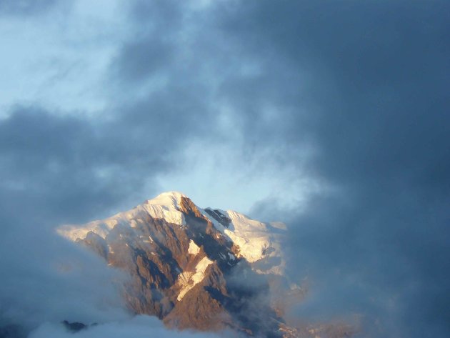 Zonnige sneeuwtop tussen de wolken