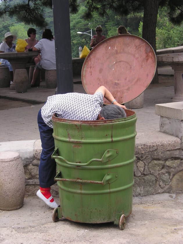 Bejaarde vrouw op zoek naar plastic flesjes.