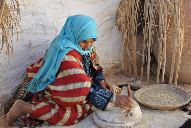 Berbervrouw maalt granen in grotwoning Matmata