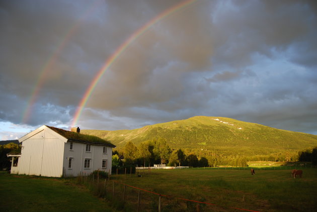 Dubbele regenboog boven oud Noors huis.