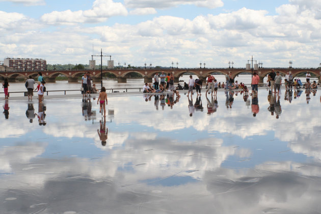 Kinderen spelen op een met water besproeit plein.