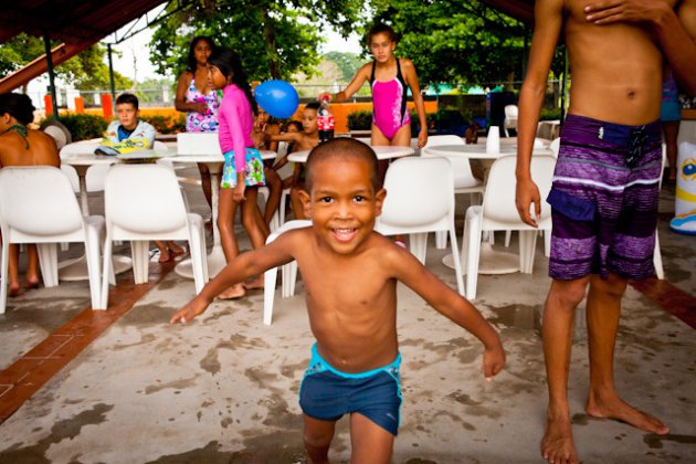 small boy running towards the photographer at a swiming party
