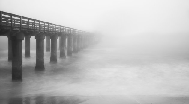 De oude aanlegsteiger van Swakopmund verdwijnt in de mist.