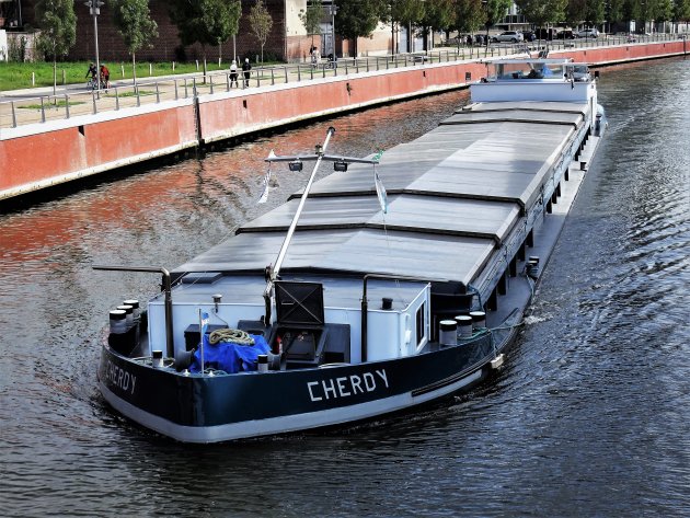 Een aak passeert Kortrijk op de Leie