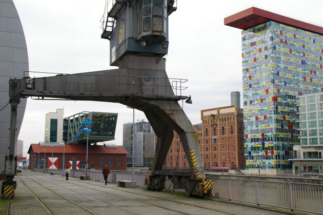 Oude havenkraan en moderne pakhuizen