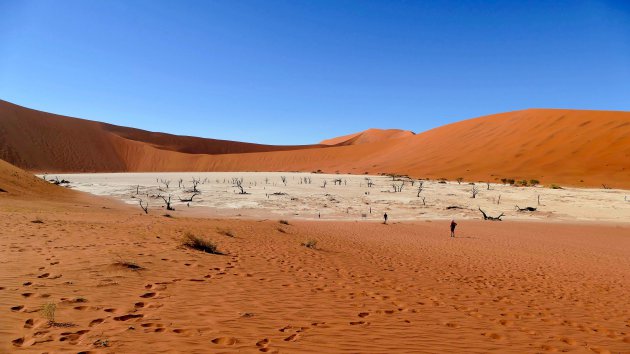 een witte kleivlakte omringd door hoge duinen