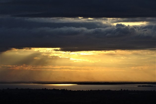 Ondergaande zon tussen de wolken.