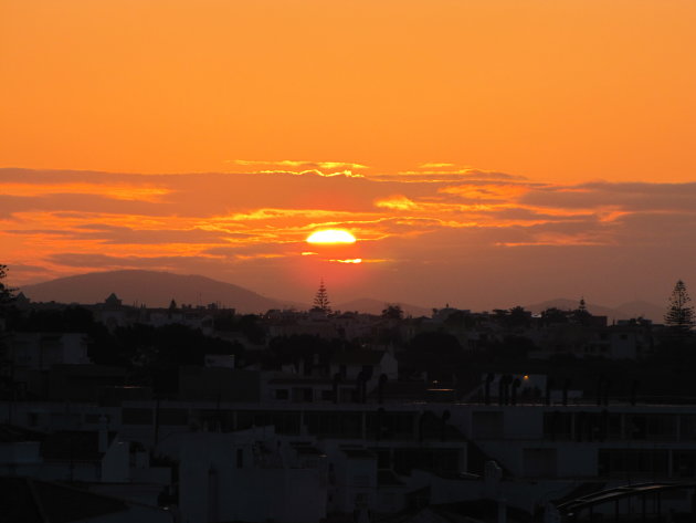 de zon kleurt de lucht oranje en het dorp ontwaakt