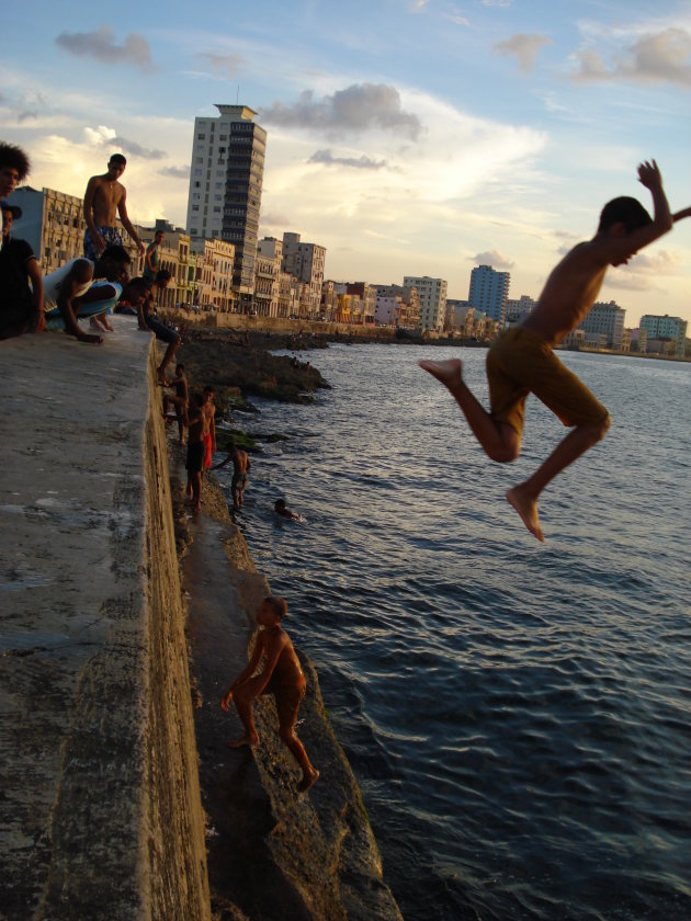 Jongen springt van de kade aan de boulevard in Havanna