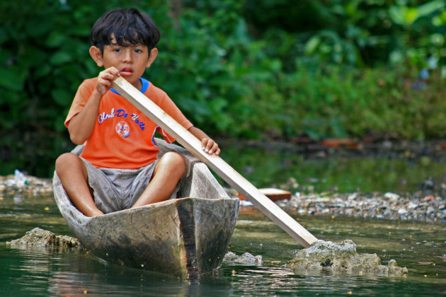 Jongetje in primitieve kano