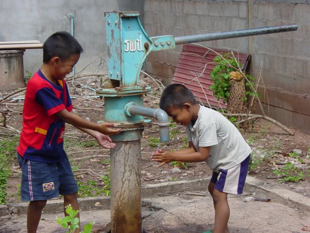 kinderen bij waterpomp in Thais dorp