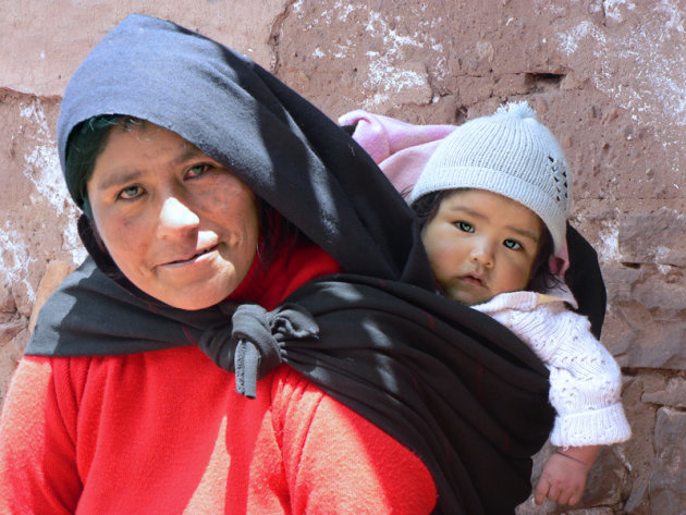 Moeder draagt dochtertje op de rug op Taquile