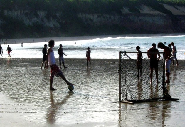 Voetballende jongeren op het strand