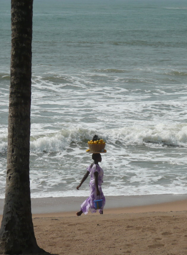 Vrouw met fruit op het strand in Elmina