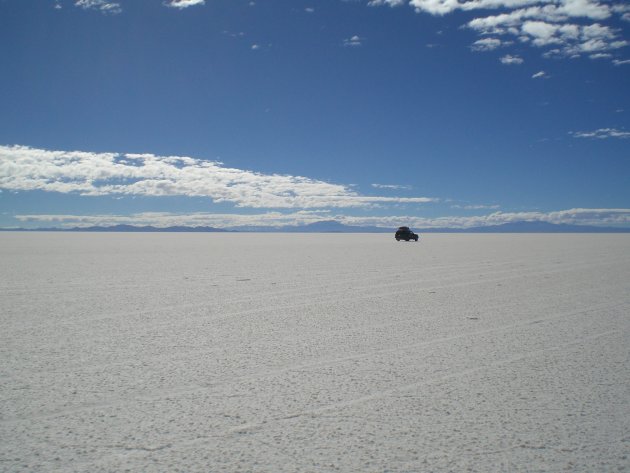 Een jeep op de uitgestrekte zoutvlakten van Bolivia
