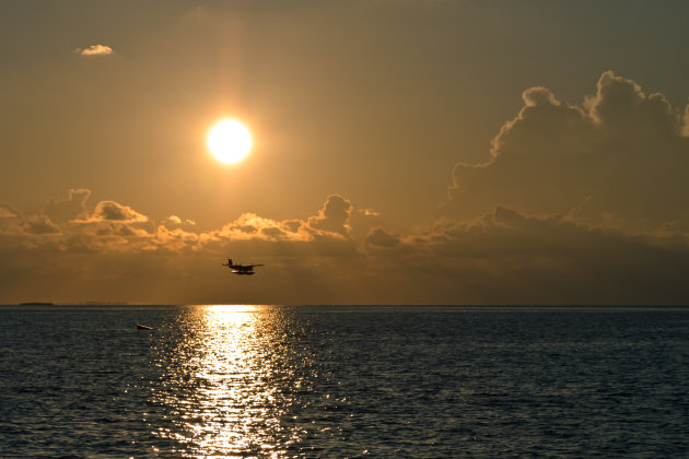 Watervliegtuig landt bij laagstaande zon