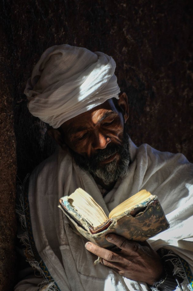 Gelovige die de bijbel leest in een rotskerk in Lalibela
