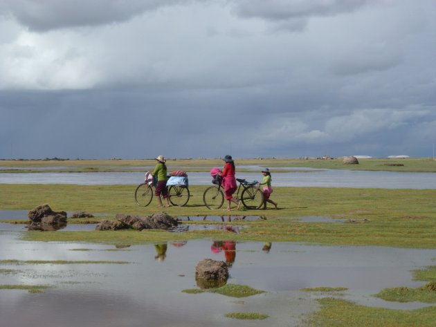 Een Boliviaans gezin op weg naar het dorp in regenseizoen.