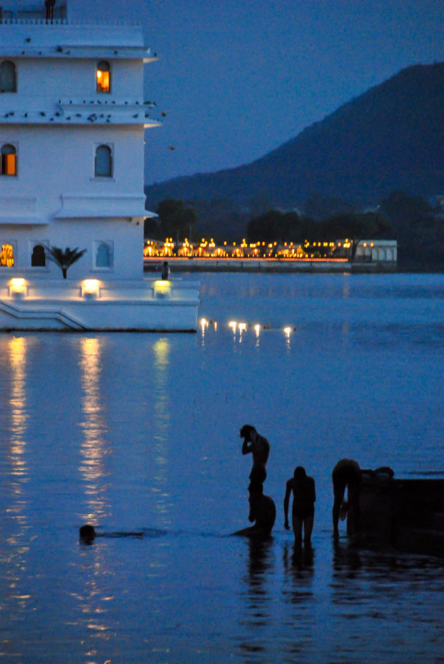 Mannen baden in het avondlicht nabij een waterpaleis in Udaipur